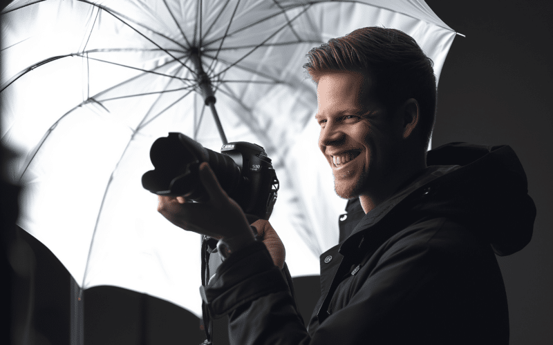 Photographe souriant utilisant un parapluie blanc lors d'une séance photo